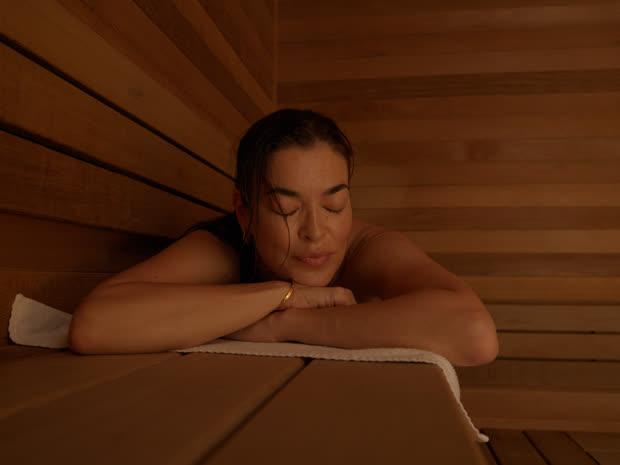 A guest smiling with her eyes closed in the sauna